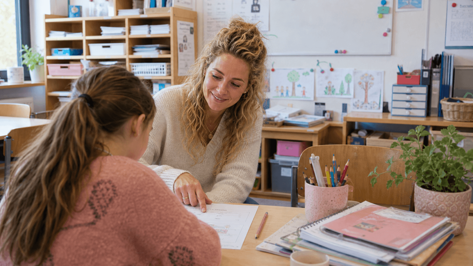 Leerkracht helpt een leerling in de klas